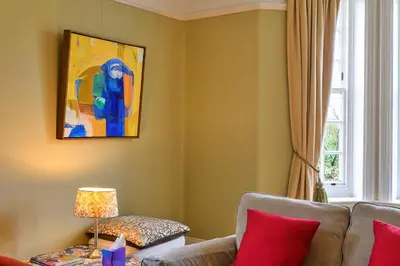 a living room with a couch and a painting on the wall at Finest Retreats - Edwardian Country House - 9 Bed, Sleeping up to 21 in Longtown