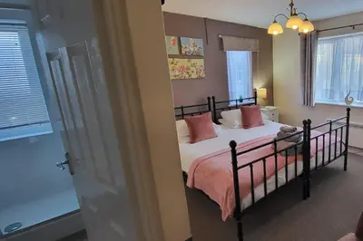 a bedroom with a bed with pink pillows on it at Ferndene Guest House in Keswick