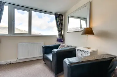 a living room with a couch and two windows at Ferndene Guest House in Keswick