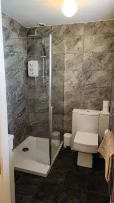 a bathroom with a toilet and a glass shower at Ferndene Guest House in Keswick