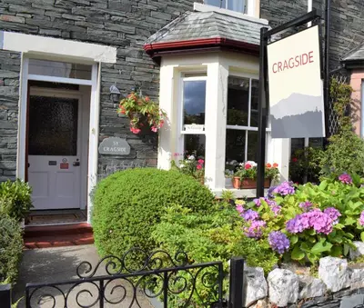 a sign in front of a house with flowers at Cragside Guest House in Keswick