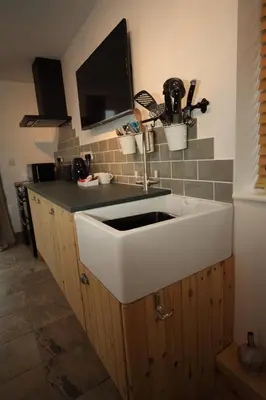 a kitchen with a white sink and a tv at Lynton Lodge Studios in Keswick
