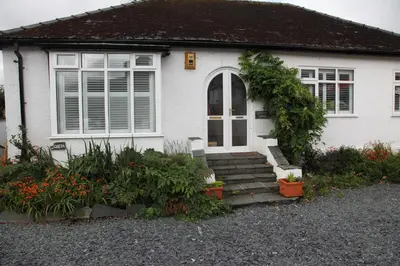 a white house with some plants in front of it at Lynton Lodge Studios in Keswick