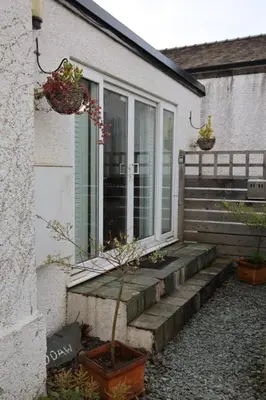 a house with a porch with potted plants on it at Lynton Lodge Studios in Keswick
