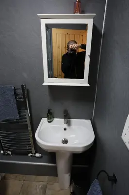 a man taking a picture of a sink in a bathroom at Lynton Lodge Studios in Keswick