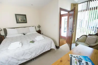 a bedroom with a bed with white sheets and a chair at Graysonside in Cockermouth