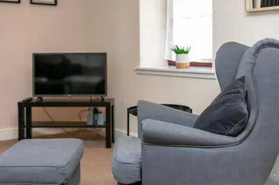 a living room with two chairs and a television at Elliot Suite No7 - Donnini Apartments in Ayr
