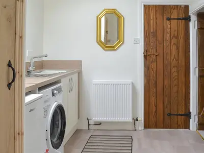 a laundry room with a washing machine and a mirror at Penfold in Dockray