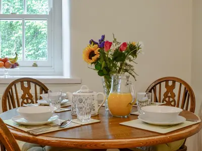 a wooden table with a vase of flowers on it at Penfold in Dockray