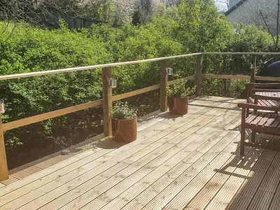 a wooden deck with two benches and two plants at Burnside in Torthorwald