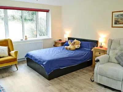 a teddy bear sitting on a bed in a bedroom at Burnside in Torthorwald