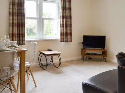 a living room with a television and a table at 6 Elm Court in Keswick