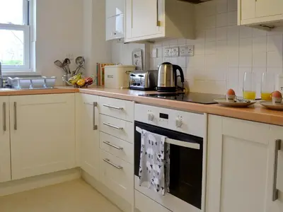a kitchen with white cabinets and a stove top oven at 6 Elm Court in Keswick
