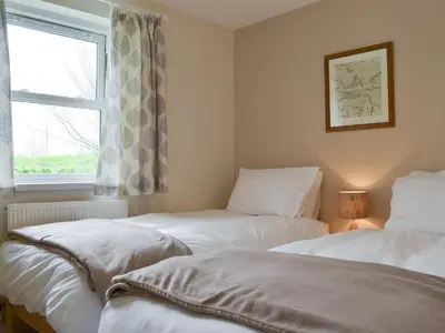 two beds in a room with a window at 6 Elm Court in Keswick