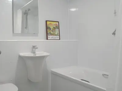 a white bathroom with a sink and a toilet and a mirror at 6 Elm Court in Keswick
