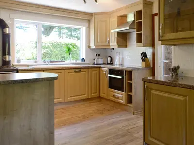 a kitchen with wooden cabinets and a large window at The Old Schoolhouse in Colfin