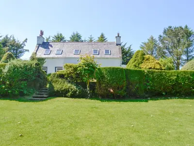 a house with a hedge in front of a yard at The Old Schoolhouse in Colfin
