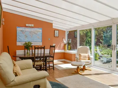 a living room with orange walls and a table and chairs at The Old Schoolhouse in Colfin