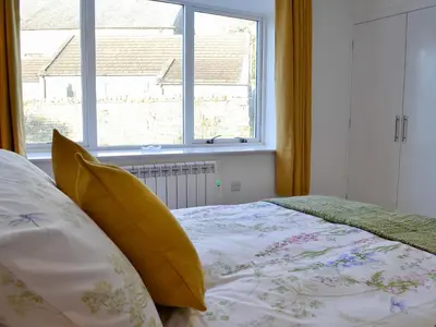 a bedroom with a bed with yellow pillows and a window at 3 Old Posting Stables in Gatehouse of Fleet
