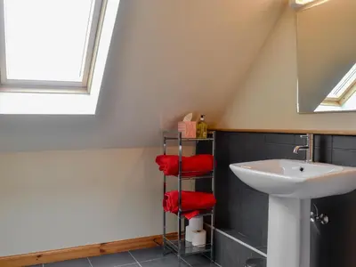 a bathroom with a sink and red towels on a shelf at The Soup Kitchen in Borgue