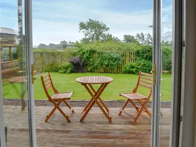 a patio with a table and two chairs on a deck at The Soup Kitchen in Borgue