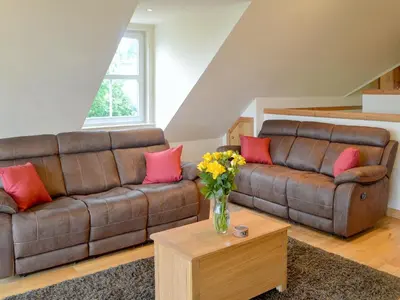 a living room with a couch and a vase of flowers on a table at The Soup Kitchen in Borgue