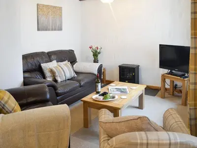 a living room with a leather couch and a coffee table at Clover Cottage in Keswick