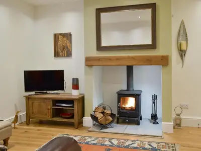 a living room with a fireplace and a tv at Riverholme in Bassenthwaite