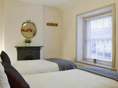 a bedroom with two beds and a mirror and a window at Riverholme in Bassenthwaite