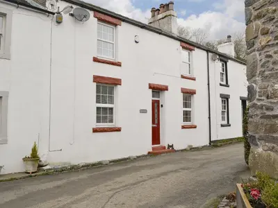 a white house with a red door on a street at Riverholme in Bassenthwaite