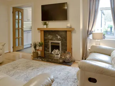 a living room with a fireplace with a tv above it at Buckle House in Gatehouse of Fleet
