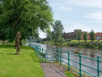 a green fence next to a river at River View in Dumfries