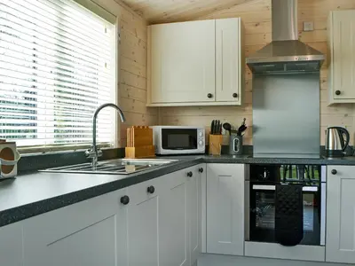 a kitchen with white cabinets and a sink and a microwave at Bransty in Keswick