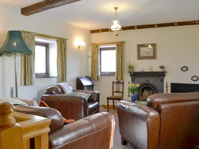 a living room with leather furniture and a fireplace at Swallows Return in Whitehaven