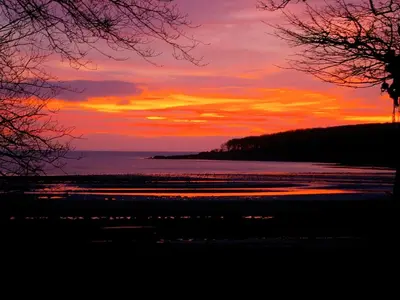 a sunset over a beach with the ocean at Shore Cottage - Uk12524 in Garlieston