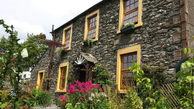a stone house with flowers in front of it at Stybeck Farm in Thirlmere