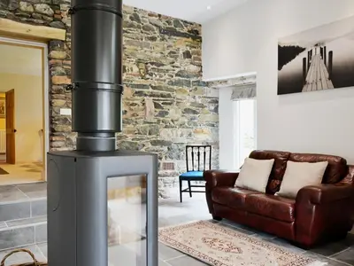 a living room with a wood stove and a couch at High Birch Close in Patterdale