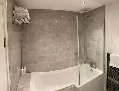 a bathroom with a shower with a tub and a sink at Maryport House in Maryport