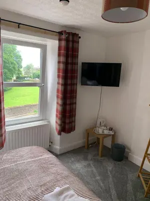 a bedroom with a bed and a tv and a window at DOVENBY SHIP in Tallentire
