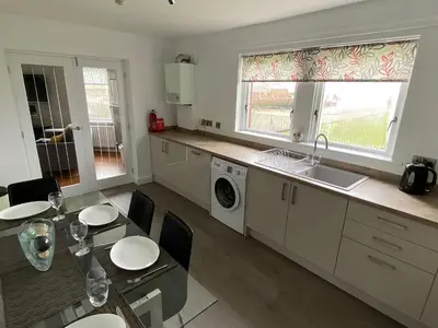 a kitchen with a table and a sink and a dishwasher at Ritson Wharf in Maryport