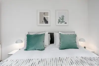 a white bedroom with a white bed with green pillows at Granary Suite No22 - Donnini Apartments in Ayr