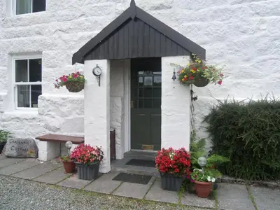 a white house with flower pots on the front door at Craignair Cottage in Dalbeattie