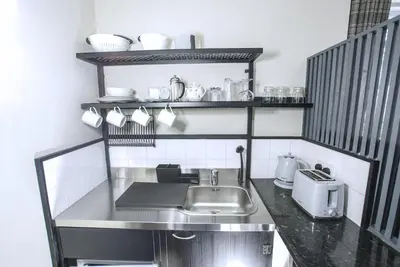 a small kitchen with a sink and shelves at Craignair Cottage in Dalbeattie