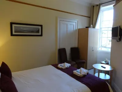 a hotel room with a bed and a table and a window at Dumfries Villa in Dumfries