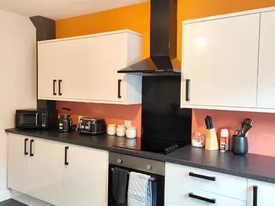 a kitchen with white cabinets and a black stove top oven at Carvetii - Phoenix House - Near Hospital, max 8 ppl in Carlisle