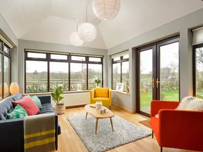 a living room with a couch and chairs and windows at Borgan Cottage in Newton Stewart