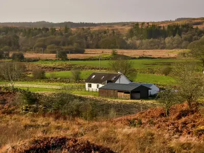 a barn in the middle of a field at Borgan Cottage in Newton Stewart