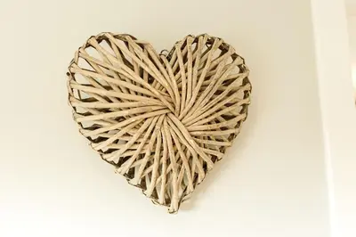 a wicker heart hanging on a white wall at Beth's Bothy in Gatehouse of Fleet