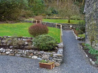 a garden with a stone wall and some plants at Squirrels Retreat - Uk30821 in Braithwaite