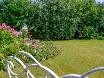 a white bench in a garden with flowers and trees at Culpee House in Newton Stewart